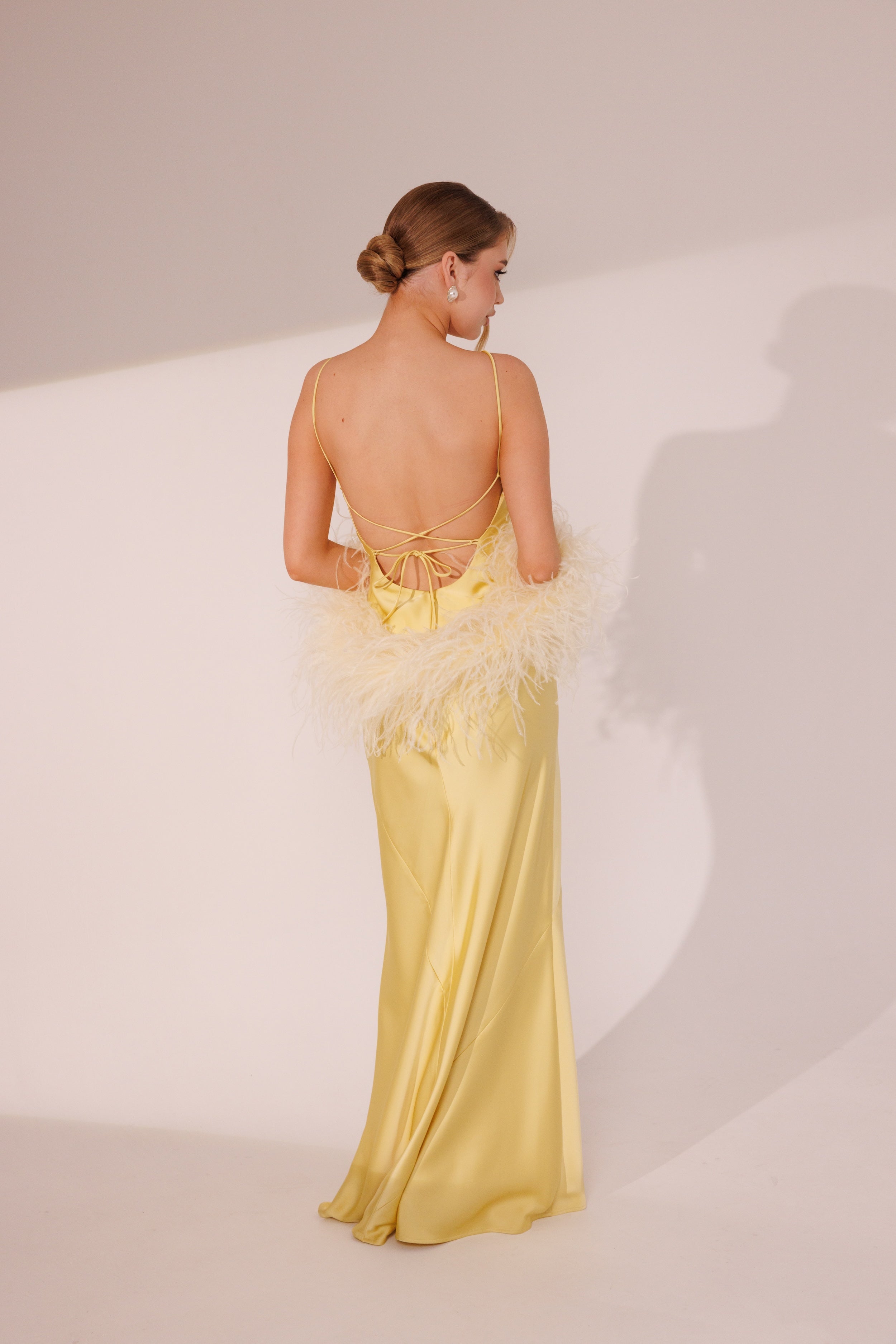 Close-up of Elara Dress in yellow color with feather boa styling