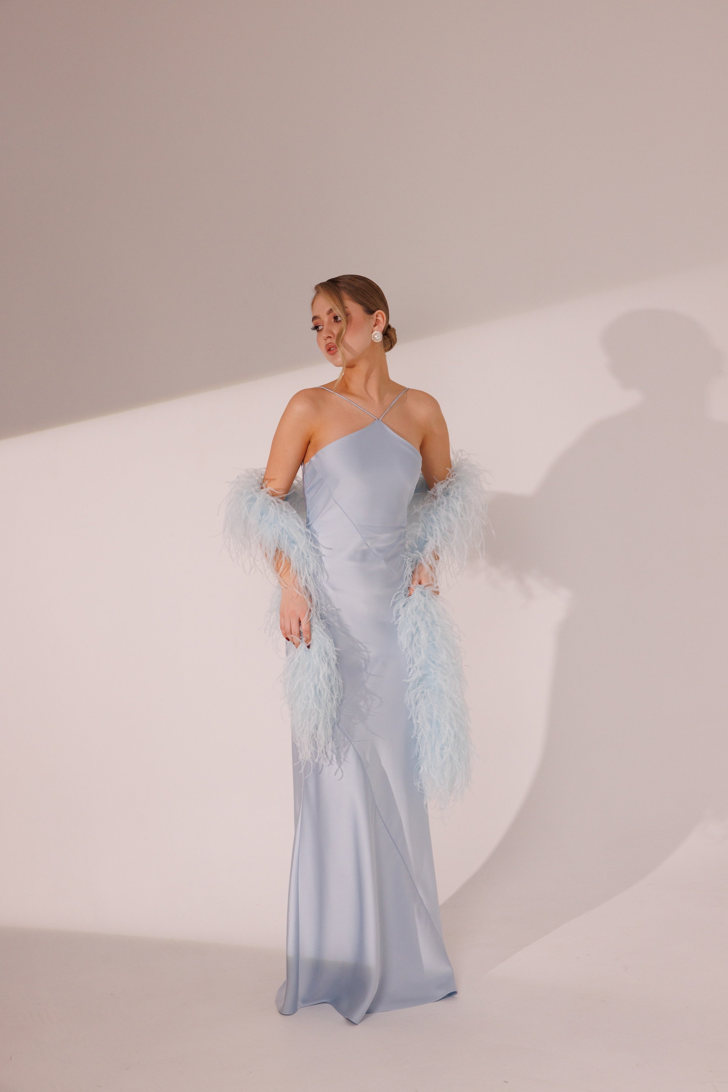 Front view of Elara blue maxi dress styled with feather boa